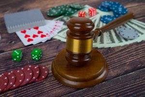 judge gavel and set of playing cards with dices, money and chips, on wooden table